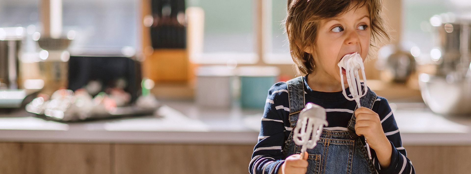 © iStock.vom/Pekic Kleiner Junge in einer Küche leckt Schlagsahne von Rührstäben ab
