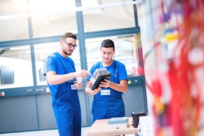 Zwei Auszubildende im Blaumann mit einem Elektromodul