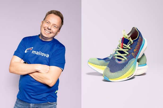 Mann lächelt, gekreuzte Arme, blaues Shirt; daneben bunte Laufschuhe auf lila Grund.