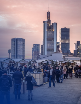 Weihnachtsmarkt und viele Besucher, vor der Frankfurter Skyline