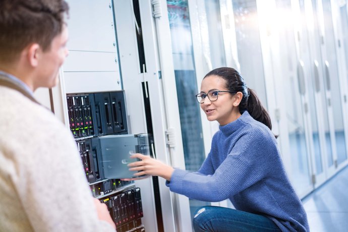 Auszubildende steckt ein Servermodul/ Festplatte in den Serverschrank