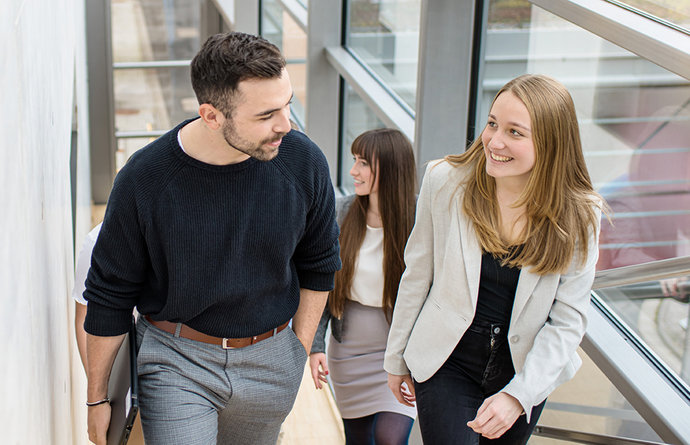 Gruppe mit Studierenden läuft eine Treppe hoch und spricht miteinander