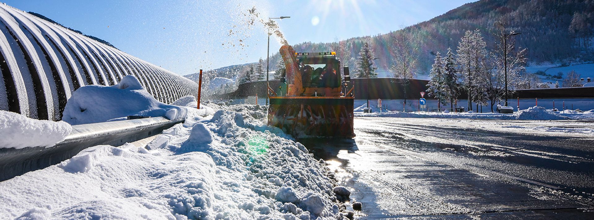 Eine verschneite Straße wird von einem Schneerpflug geräumt