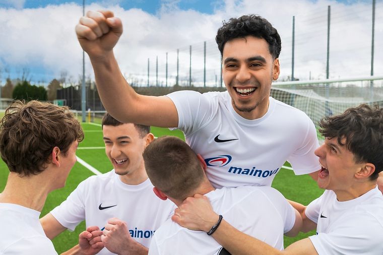 Mitglieder einer Fußballmachaft jubelnd in Mainova Trikots.