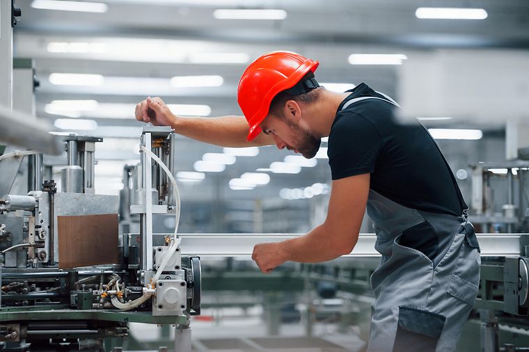 Arbeiter in einer Fabrik bearbeitet eine LED-Leiste an der Säge