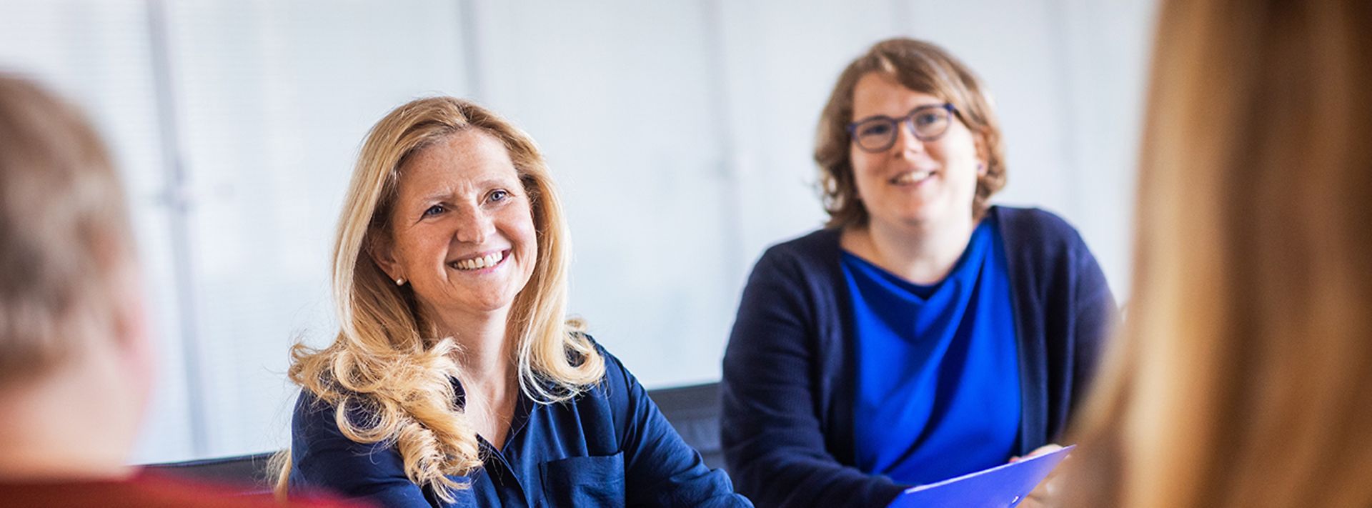 Frauen am Schreibtisch im Gespräch.