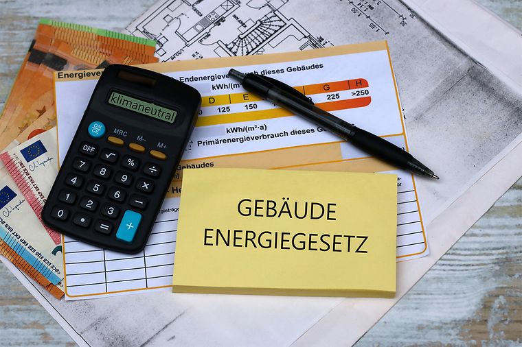 Taschenrechner und Zettel mit Aufschrift "Gebäudeenergiegesetz"