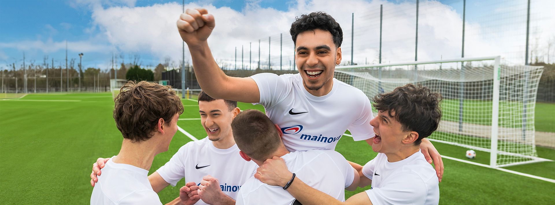 Jubelnde junge Männer beim Fußball mit weißen Mainova-Trikots