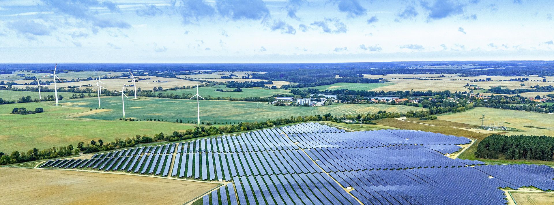 © Mainova/DennisMöbus Großer Solarpark mit Windrädern in weiter Landschaft – Symbol für erneuerbare Energie und nachhaltige Stromerzeugung.