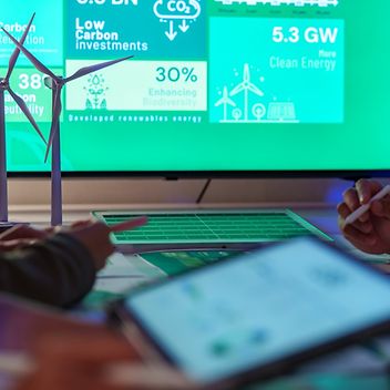 © istock - Weedezign Besprechung zwischen zwei Personen. Auf Bildschirmen werden Daten zu CO2-Bilanzen gezeigt.