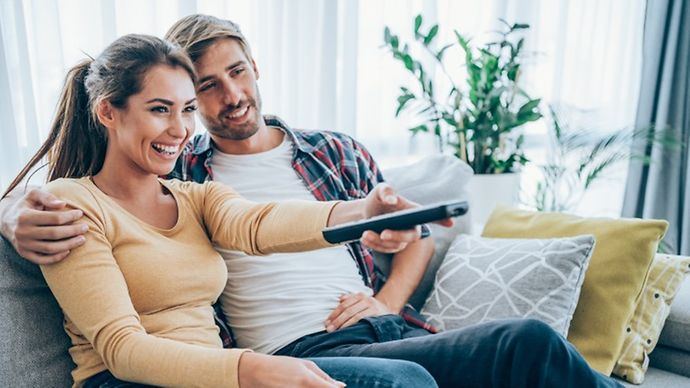 Pärchen beim Zappen auf dem Sofa