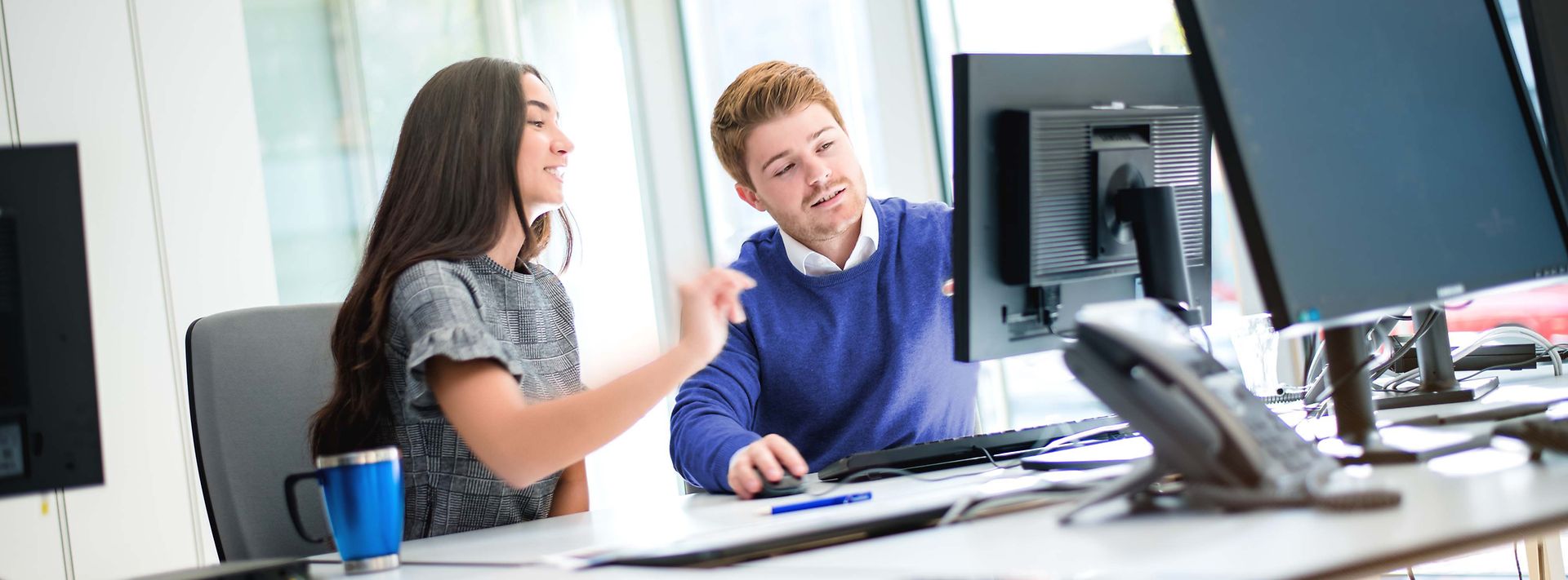 Zwei Studierende sitzen am Monitor und besprechen den Sachverhalt am Monitor